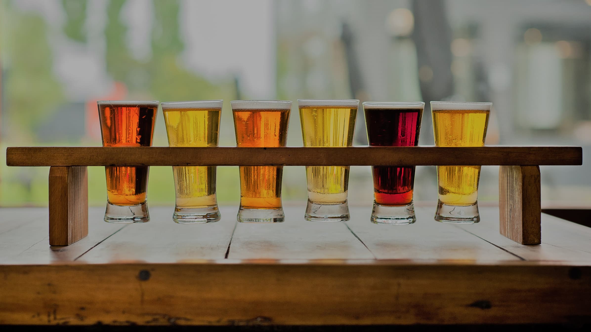 Six different types of beer displayed in glasses on a stand.